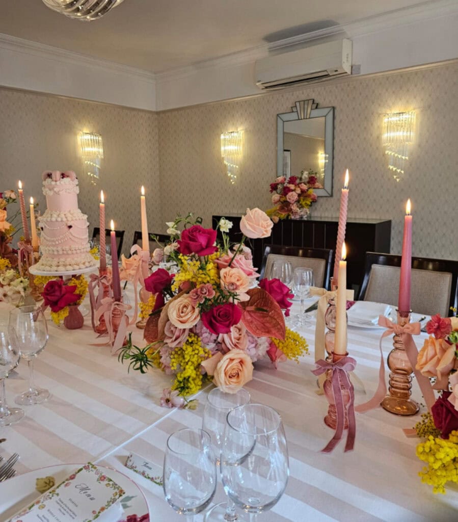 Bright and intimate wedding tablescape at The Lansdowne Club featuring yellow mimosa, Pink Floyd roses, peach and pale pink Sweet Avalanche roses, coral charm roses, pink Columbia hydrangea, and pink anthurium.