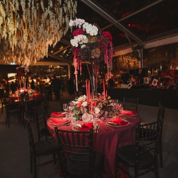 Burgundy tablescape with tall centerpiece of orchids and hydrangeas under a white wisteria ceiling at an Indian wedding in Hampshire
