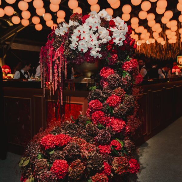 Sculptural close-up of white orchids, burgundy hydrangeas, and cascading amaranthus featured on a wedding bar at Four Seasons Hampshire