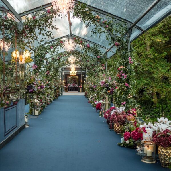 Floral-lined entrance tunnel with a mirrored canopy and crystal chandeliers for a luxury wedding celebration