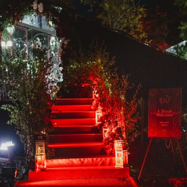 Illuminated red carpet entrance with floral arch, greenery, and welcome signage for an Indian wedding at Four Seasons Hampshire