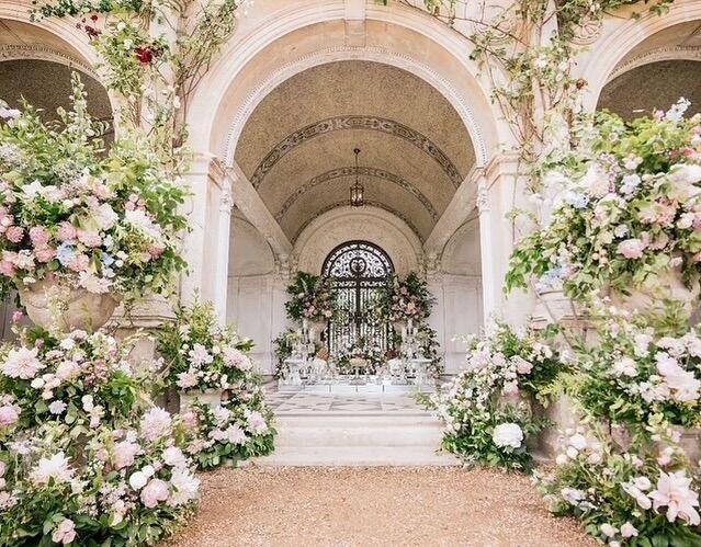 Floral urns filled with layers of pastel blooms create a graceful and inviting pathway to a day full of love.